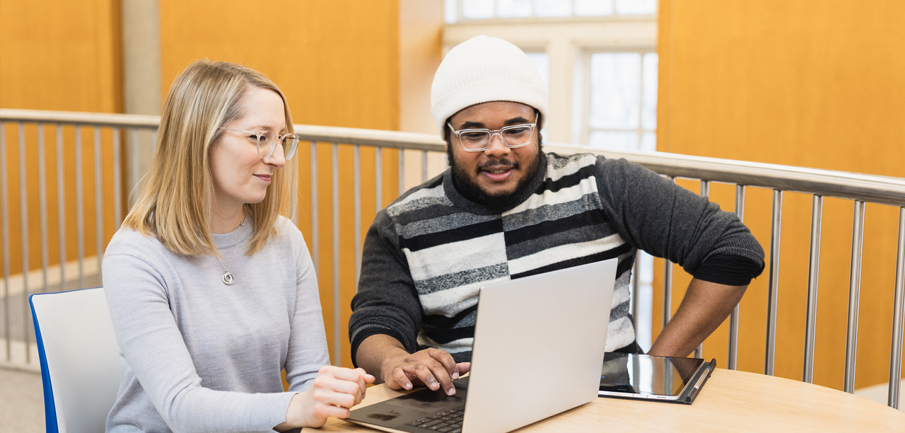 Two people working on a laptop together.